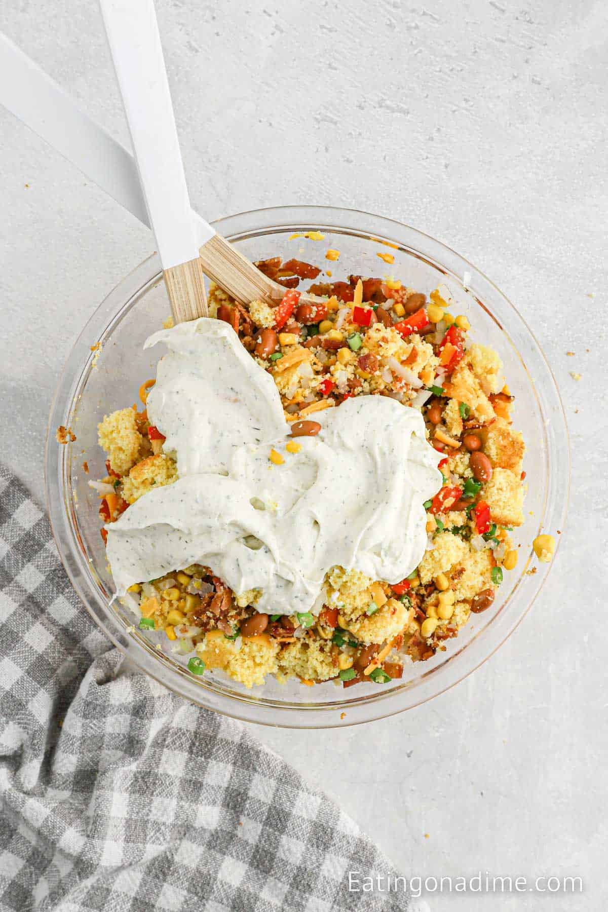 Topping the dressing with the cornbread salad ingredients