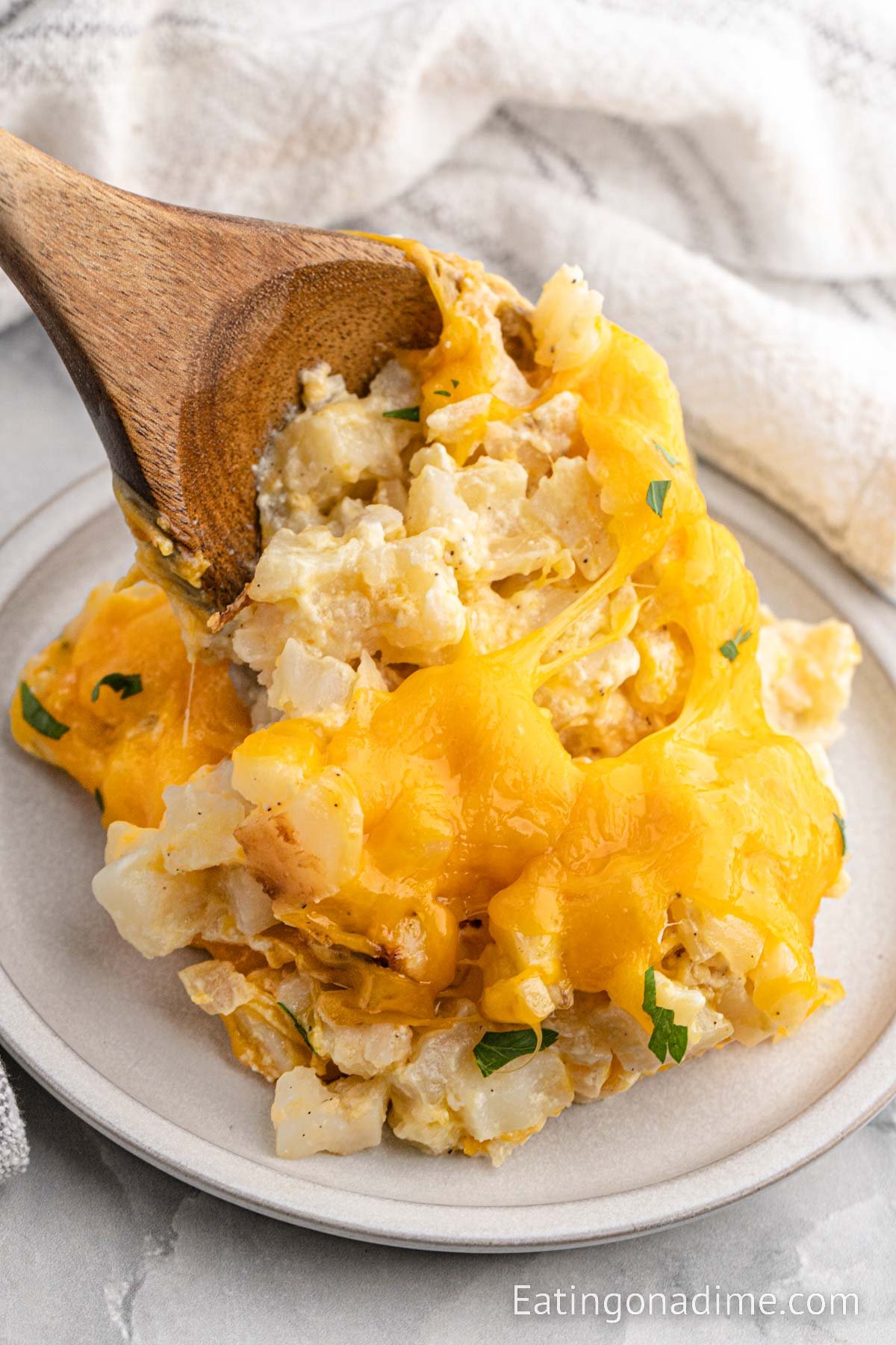 Funeral potatoes on a wood spoon on a plate