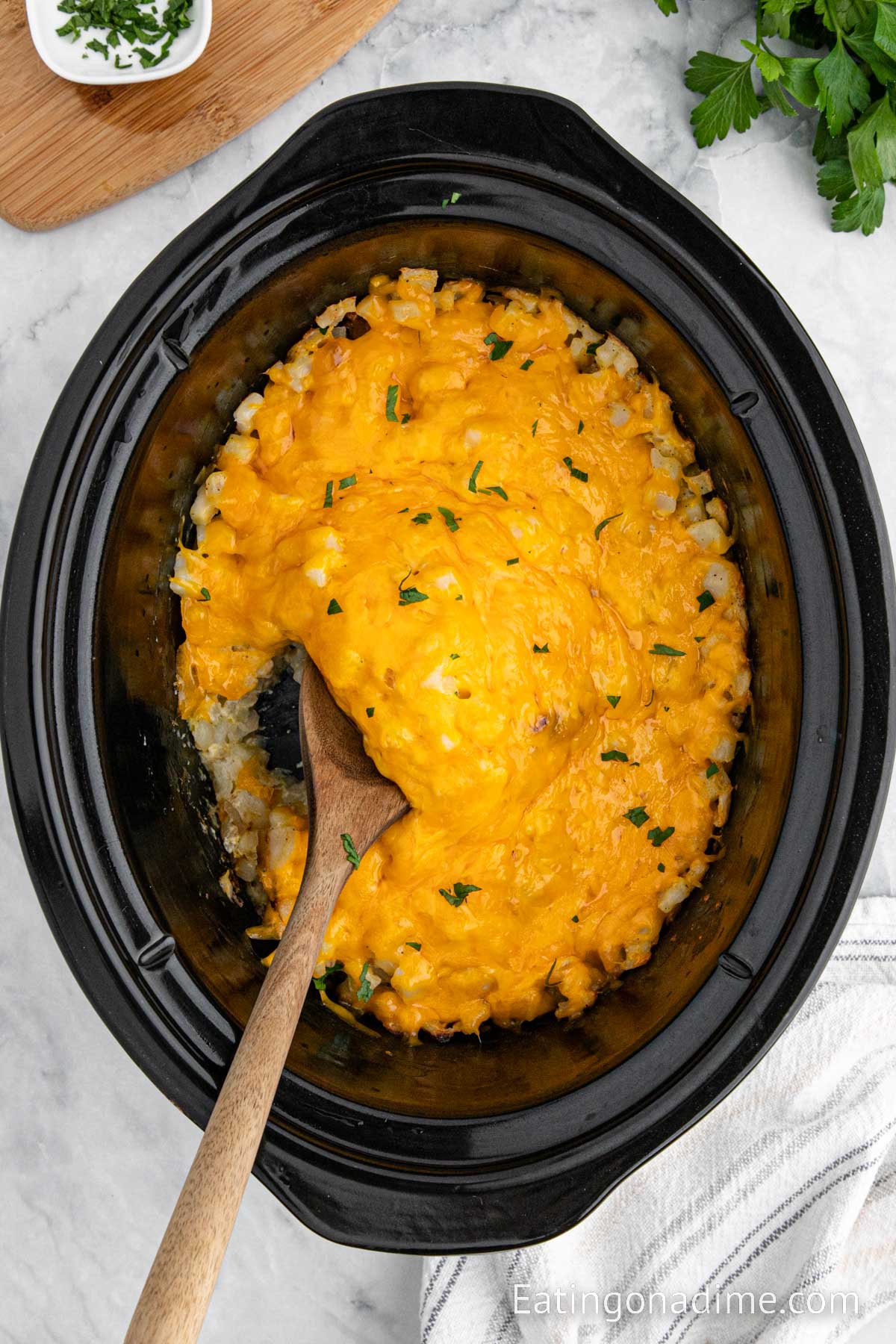 Funeral potatoes in the crock pot with a wooden spoon