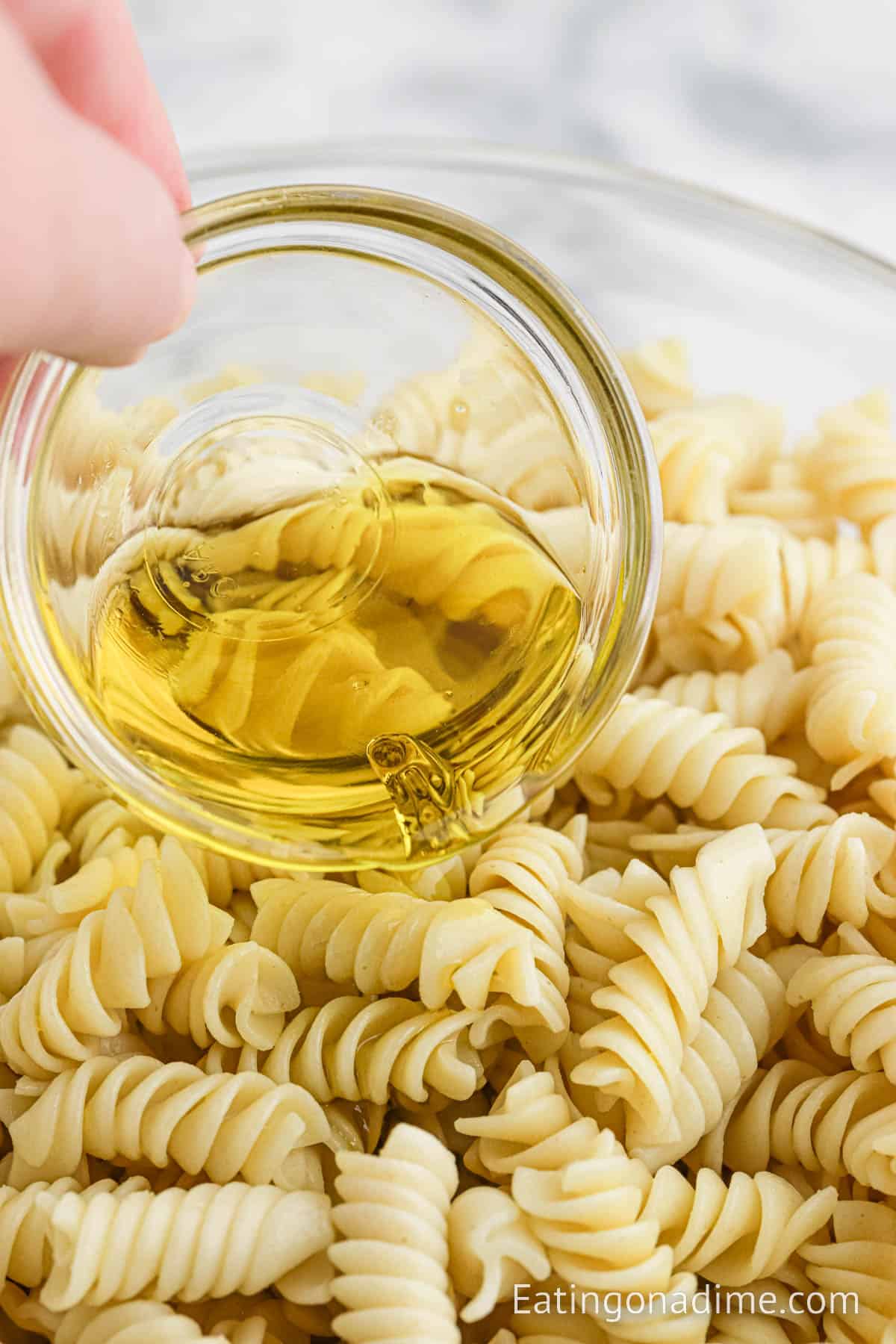 Pouring oil onto the cooked pasta