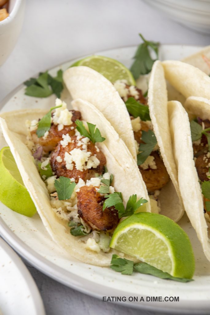Shrimp tacos on a plate with lime wedges