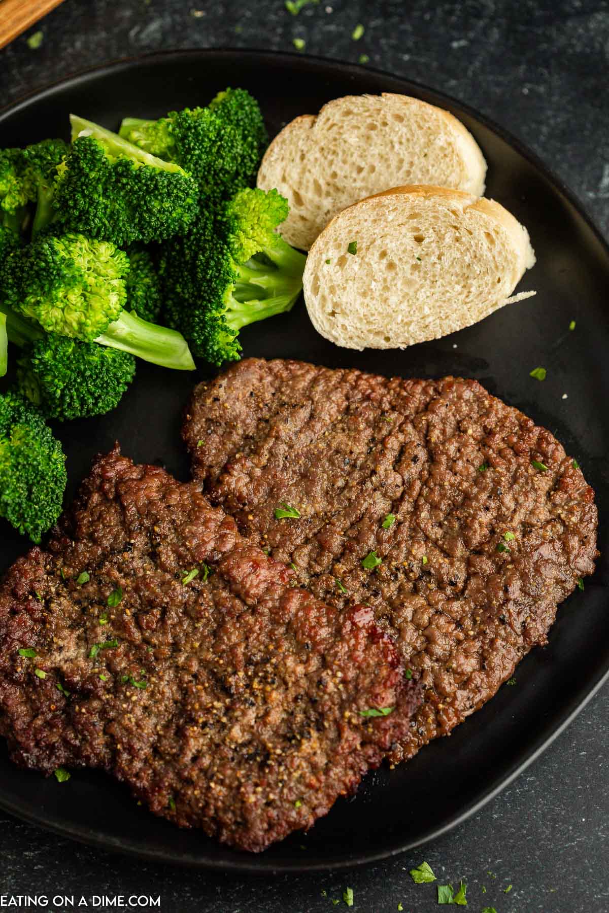 Cube steak on a plate with broccoli and french bread