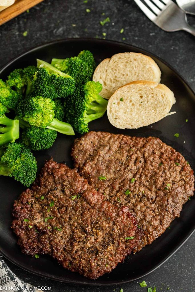 Cube steak on a plate with broccoli and french bread