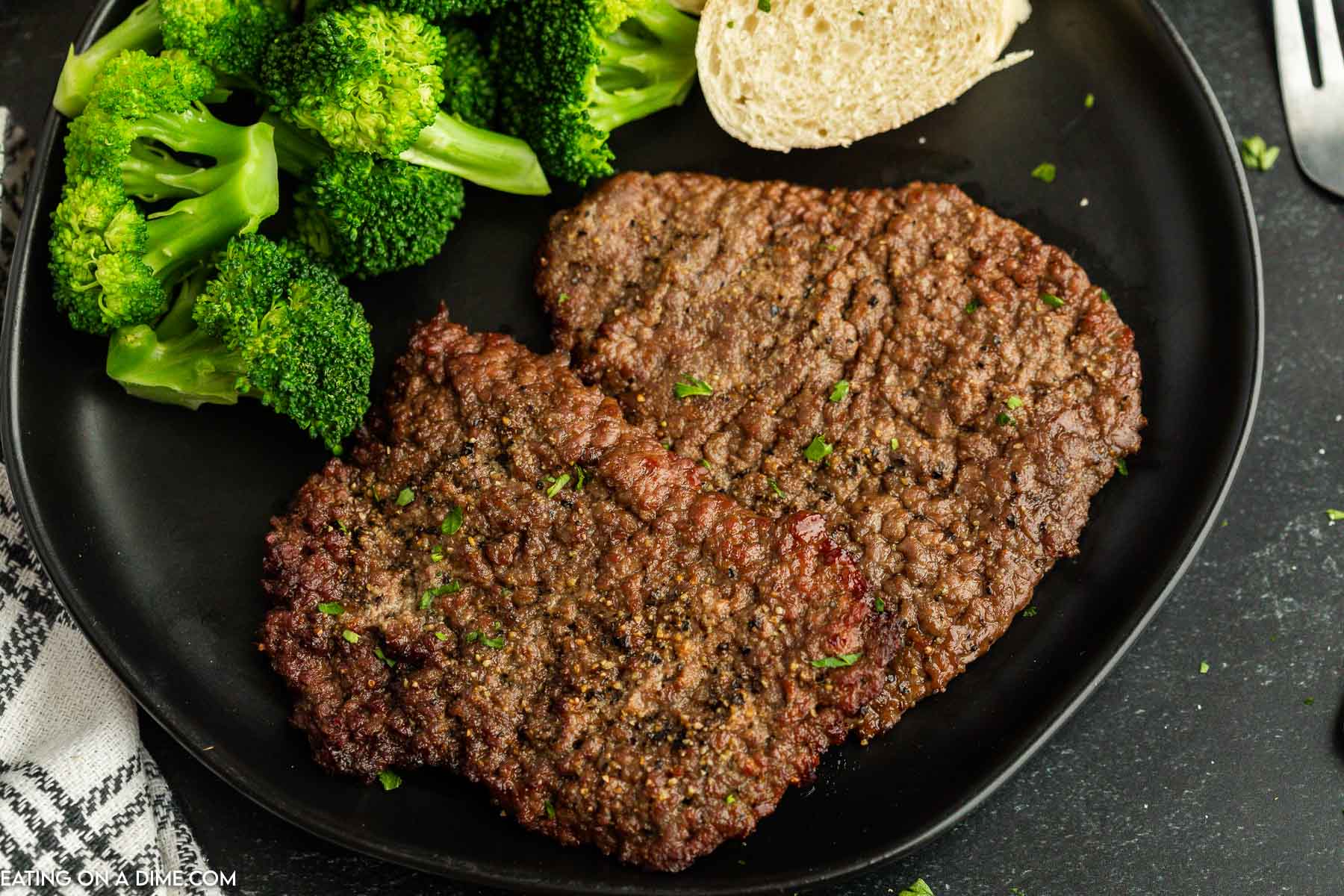 Cube steak on a plate with broccoli and french bread