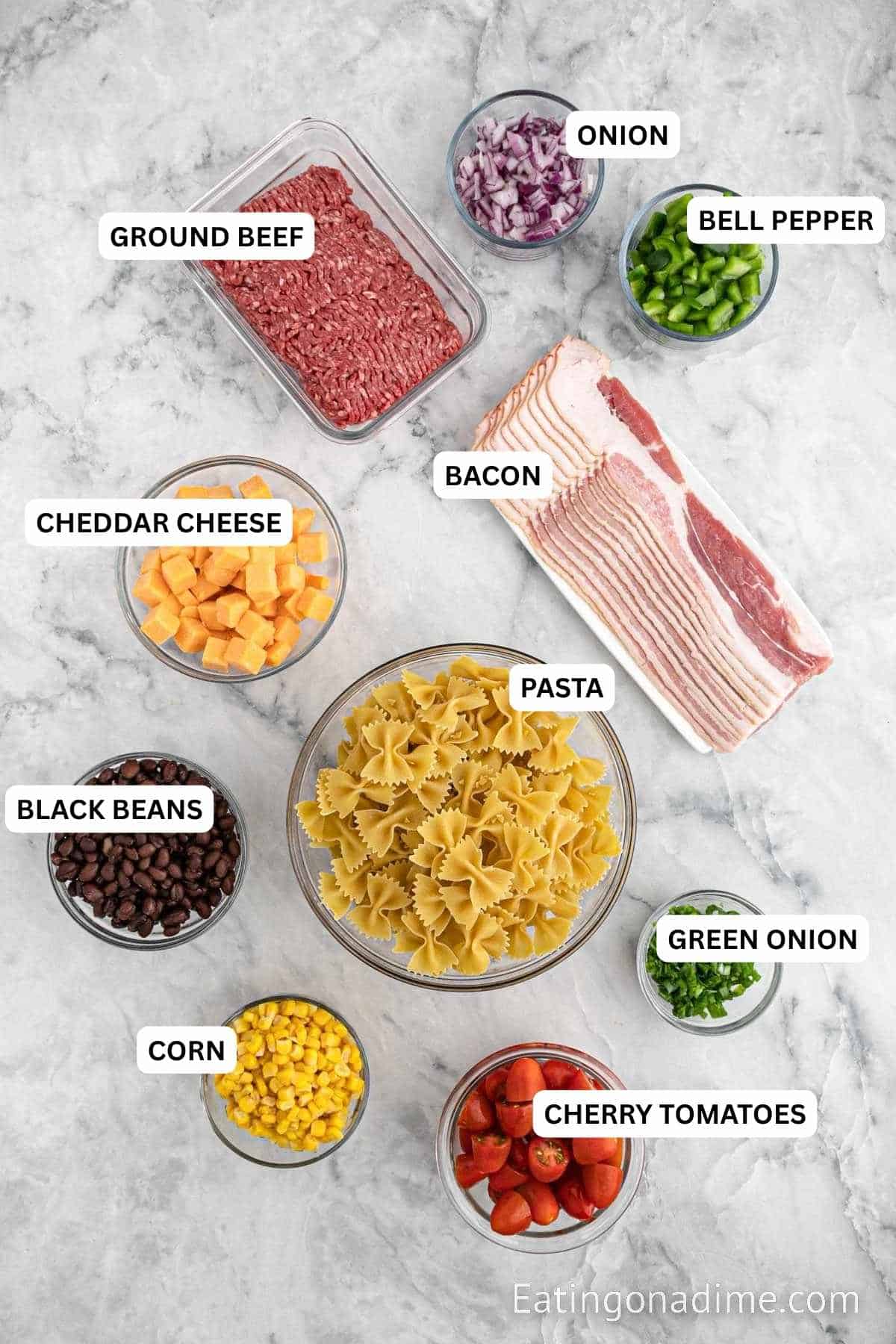 Ingredients for recipe: onion, bell pepper, ground beef, bacon, cheddar cheese, pasta, black beans, corn, green onion and cherry tomatoes.