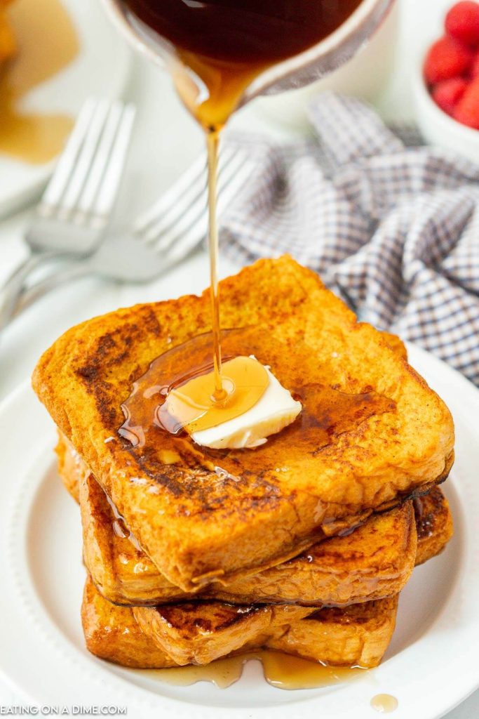 French Toast stacked on a plate with syrup and butter