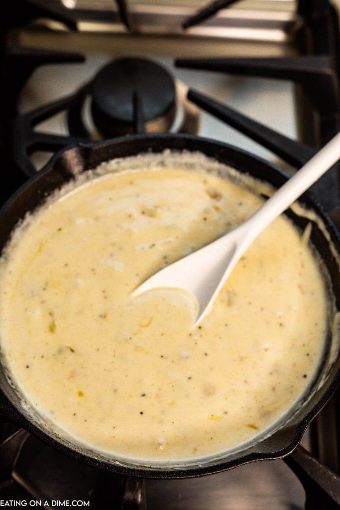 Stirring the queso in a cast iron skillet with a white spoon