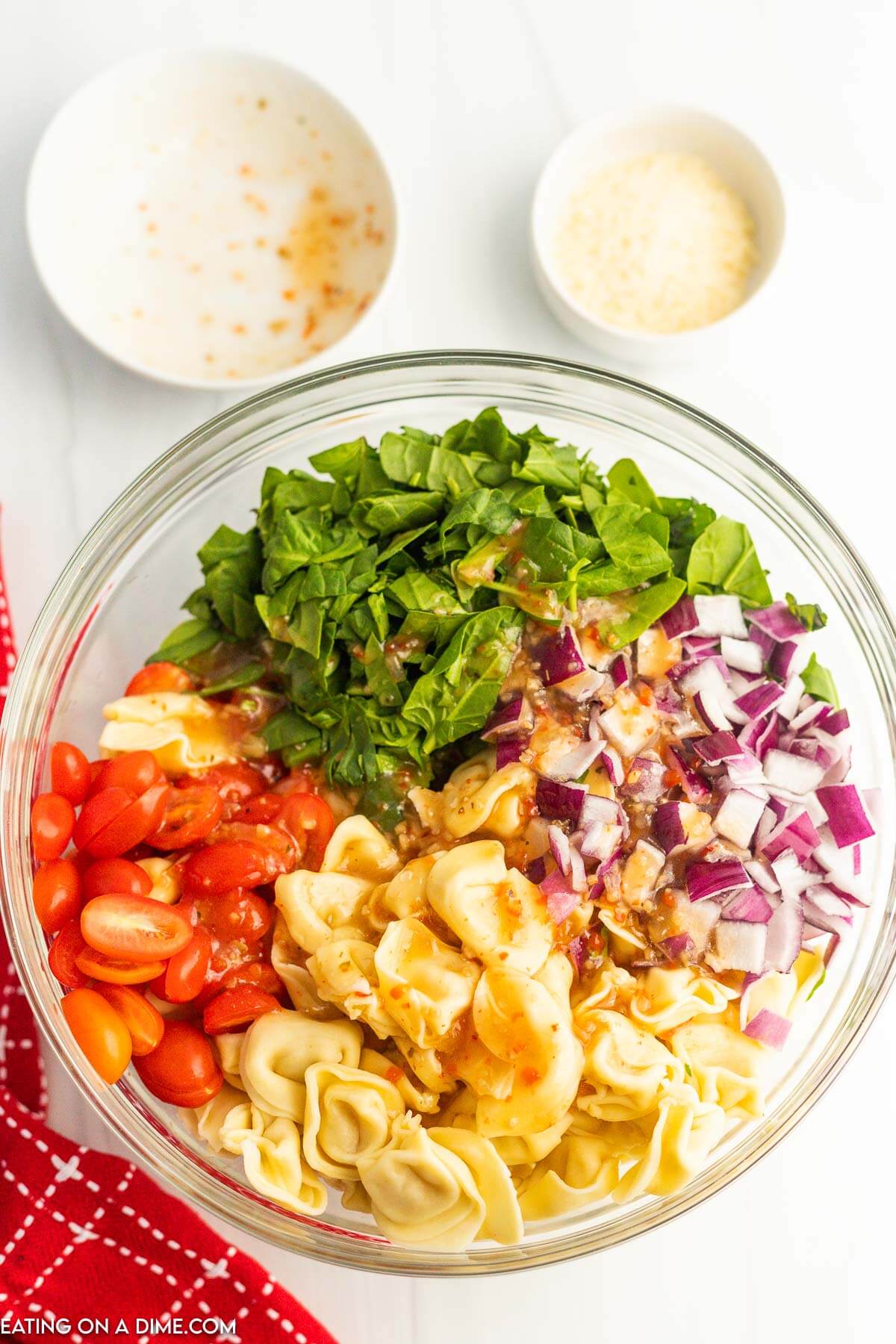 Pouring the dressing over the chopped spinach, tomatoes, and chopped onions in a bowl