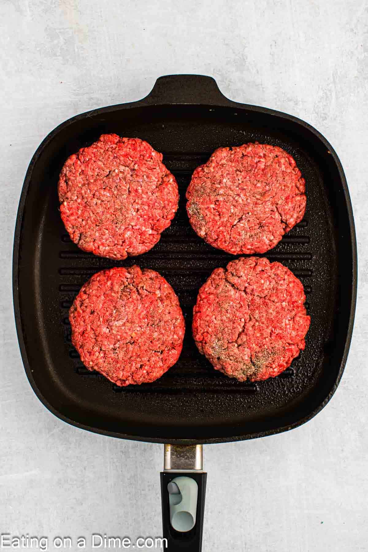 Placing the ground beef patties in a skillet