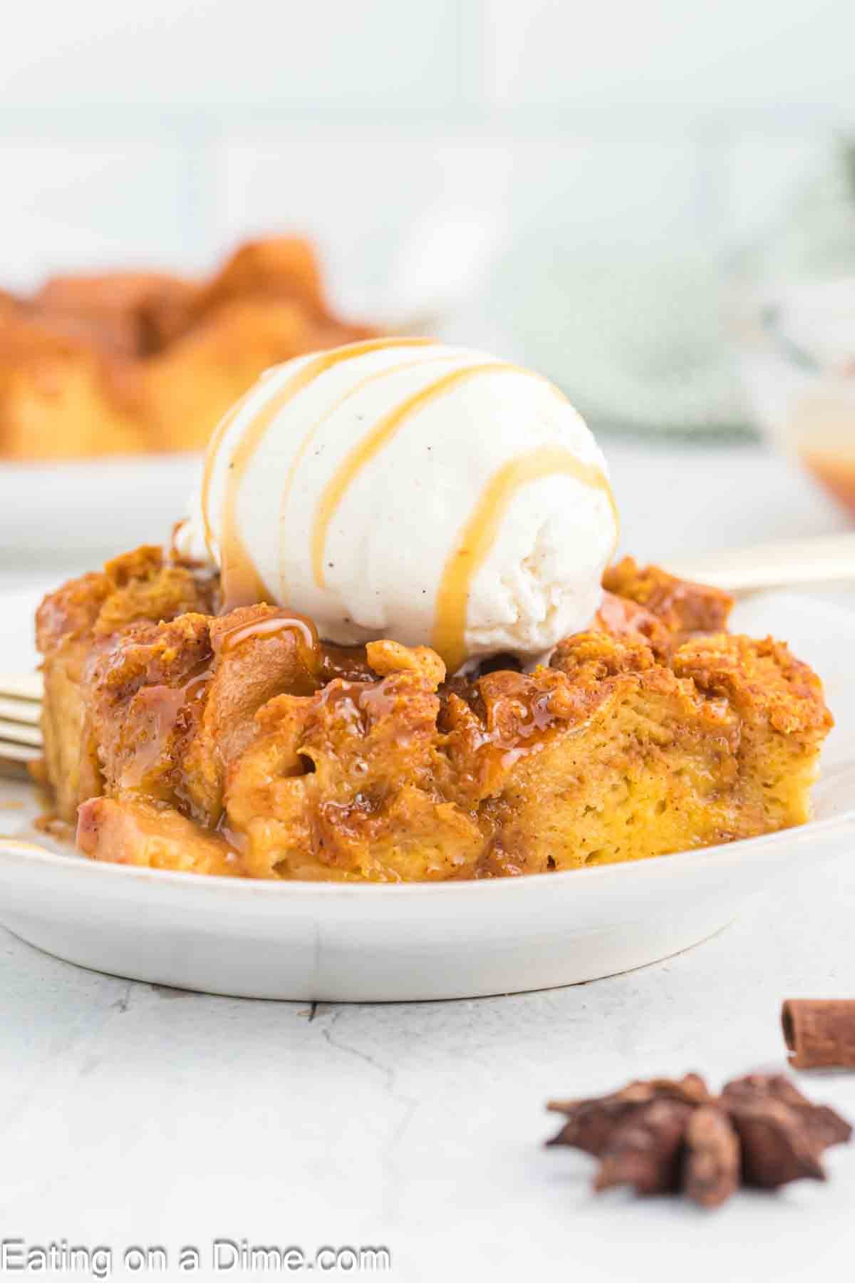 Slice of pumpkin bread pudding topped with ice cream and caramel sauce on a plate