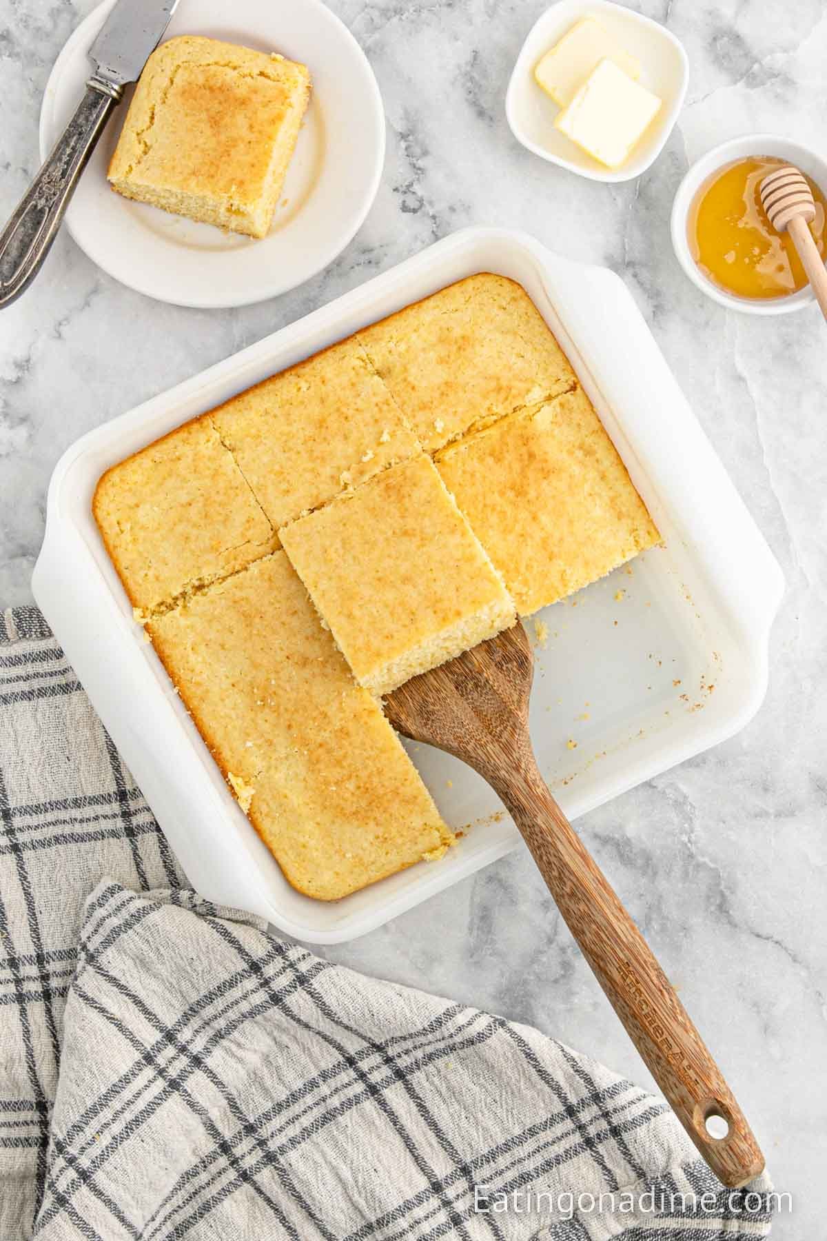 Cornbread in a baking dish with a wooden spoon