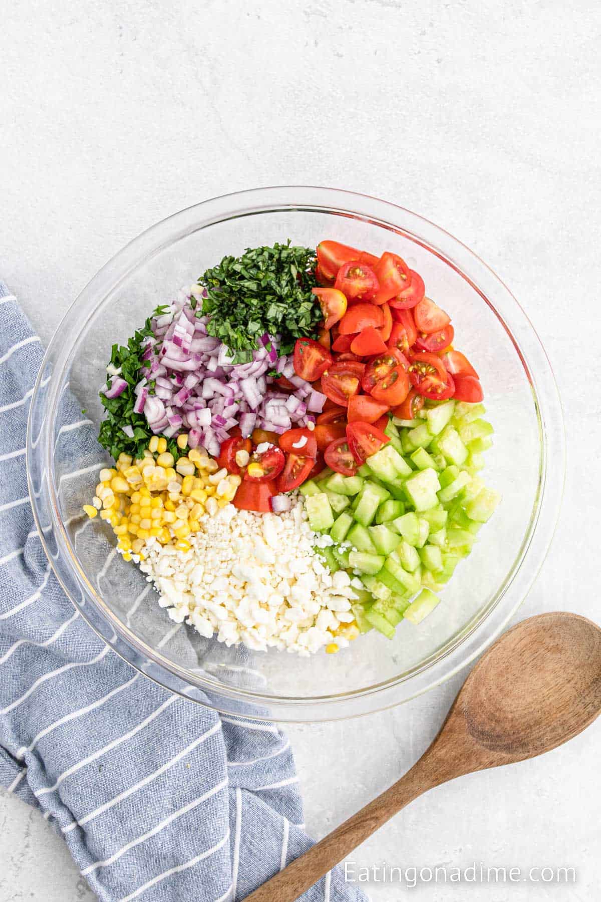 Combining the fresh vegetables and cheese together in a bowl