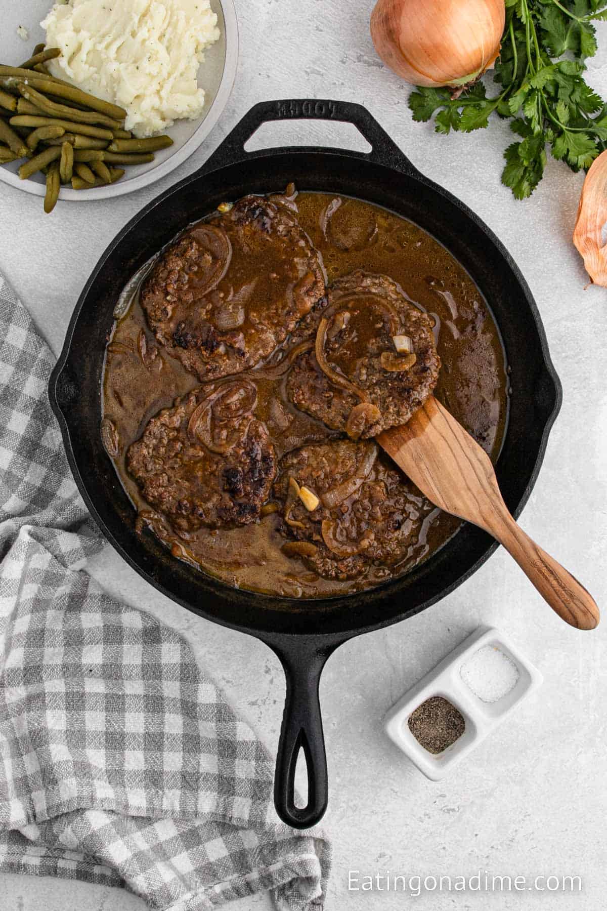 Cooked cube steak and gravy in cast iron skillet with a wooden spoon