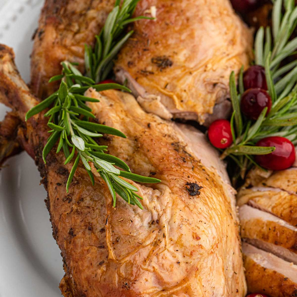 Whole Turkey legs on a platter with fresh herbs and berries