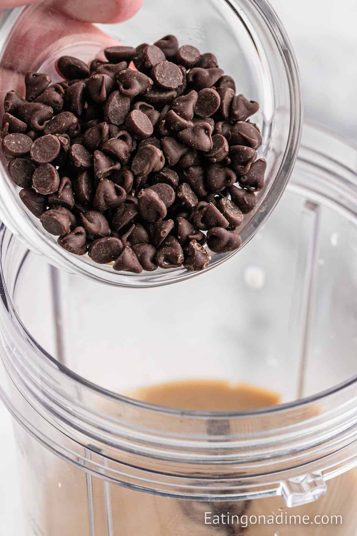 Pouring in chocolate chips into the coffee mixture in the blender cup