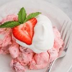 A plate topped with a strawberry angel food cake and fresh strawberries