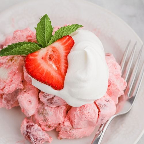 A plate topped with a strawberry angel food cake and fresh strawberries