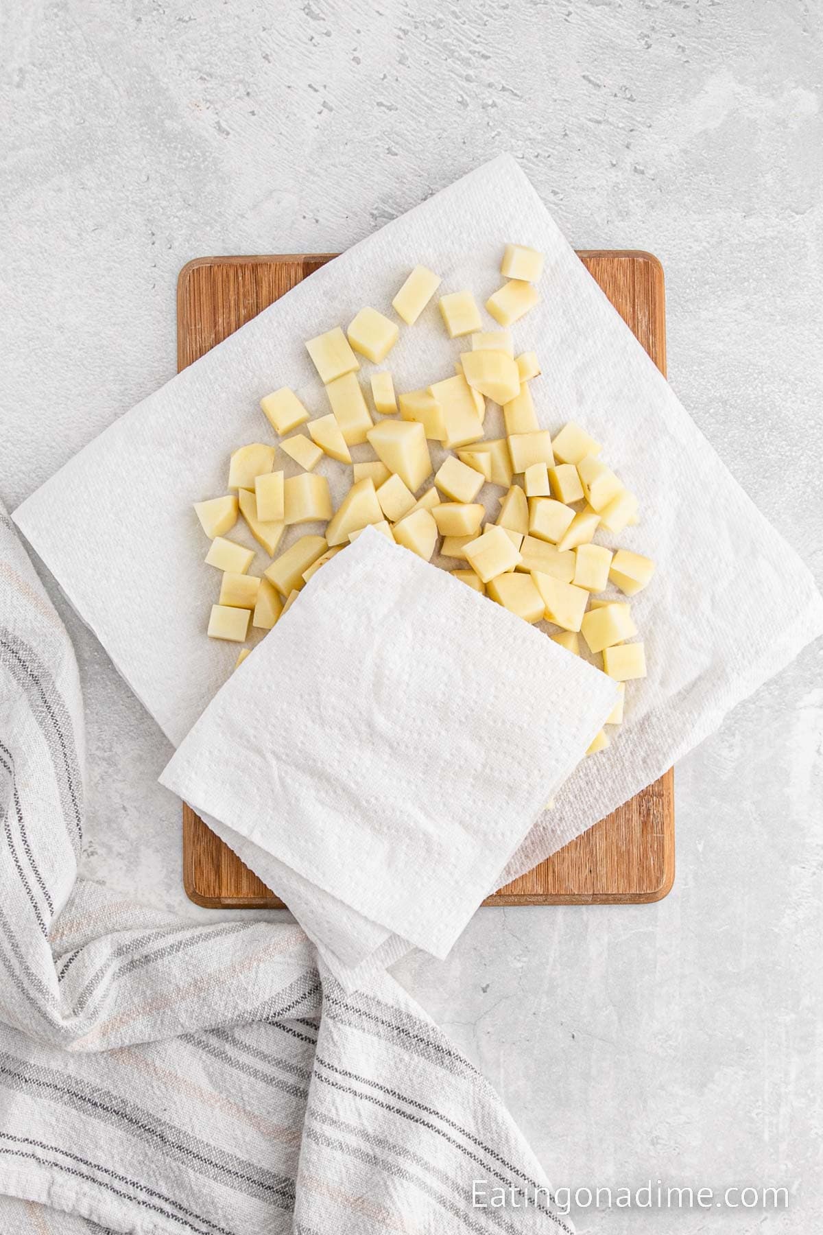 Diced potatoes on cutting board and topped paper towels