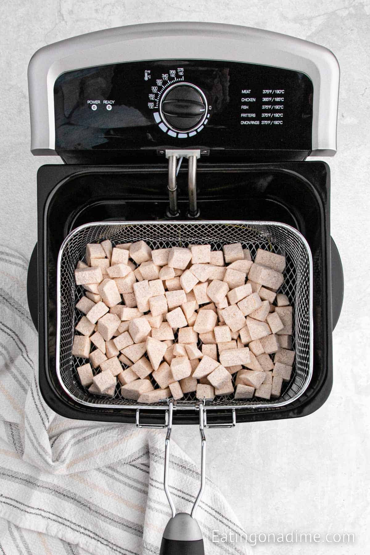 Placing the prepared diced potatoes in a fryer basket