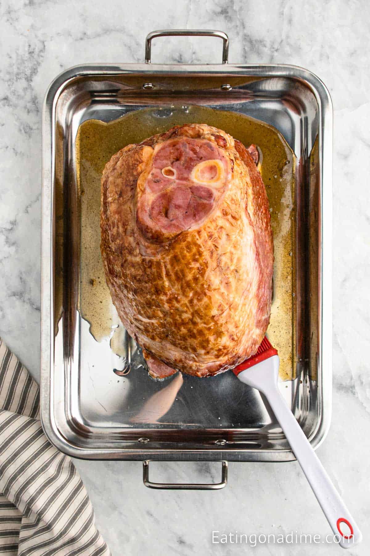 Placing ham in a roasting pan and topping with glaze