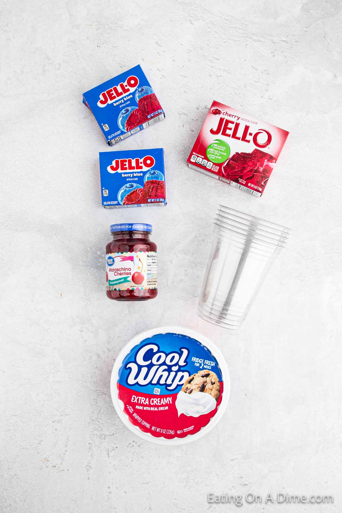 Blue Jello and cherry jello and a jar of maraschino cherries and clear cups