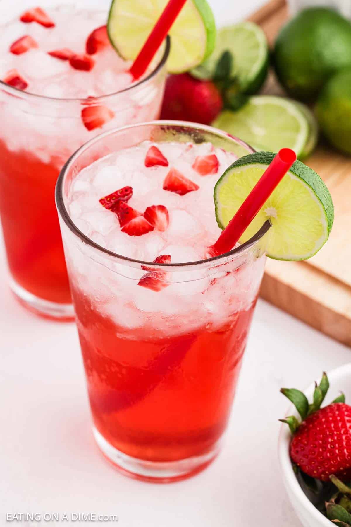 Glass of strawberry limeade topped with diced strawberries and a lime wedge on the rim.