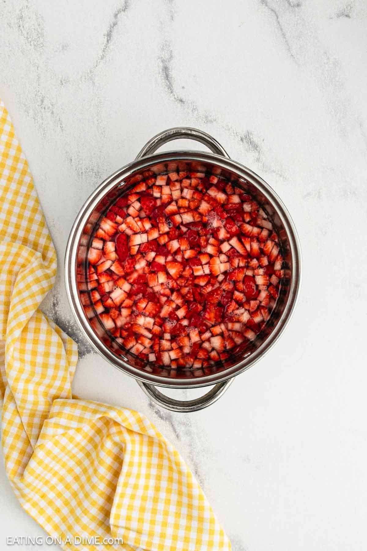 Diced strawberries in a large pot with water.