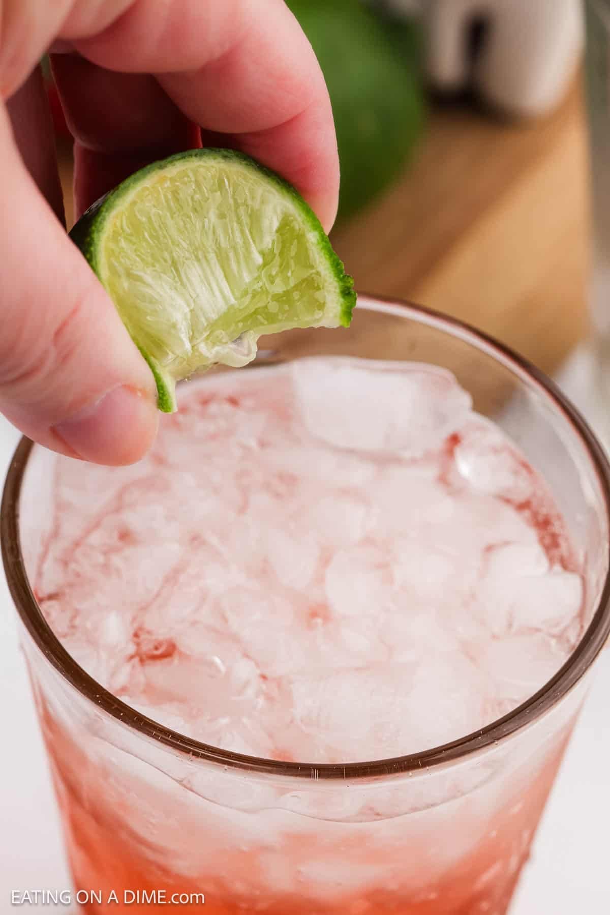 Squeezing fresh lime into the glass of Sprite.