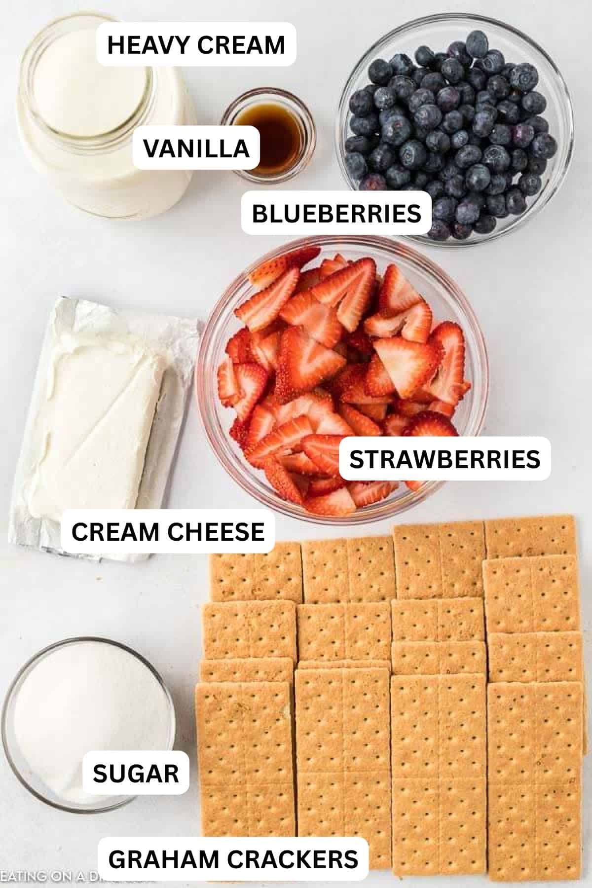 Picture of ingredients: heavy whipping cream, vanilla, cream cheese, sugar, graham crackers, blueberries, strawberries.