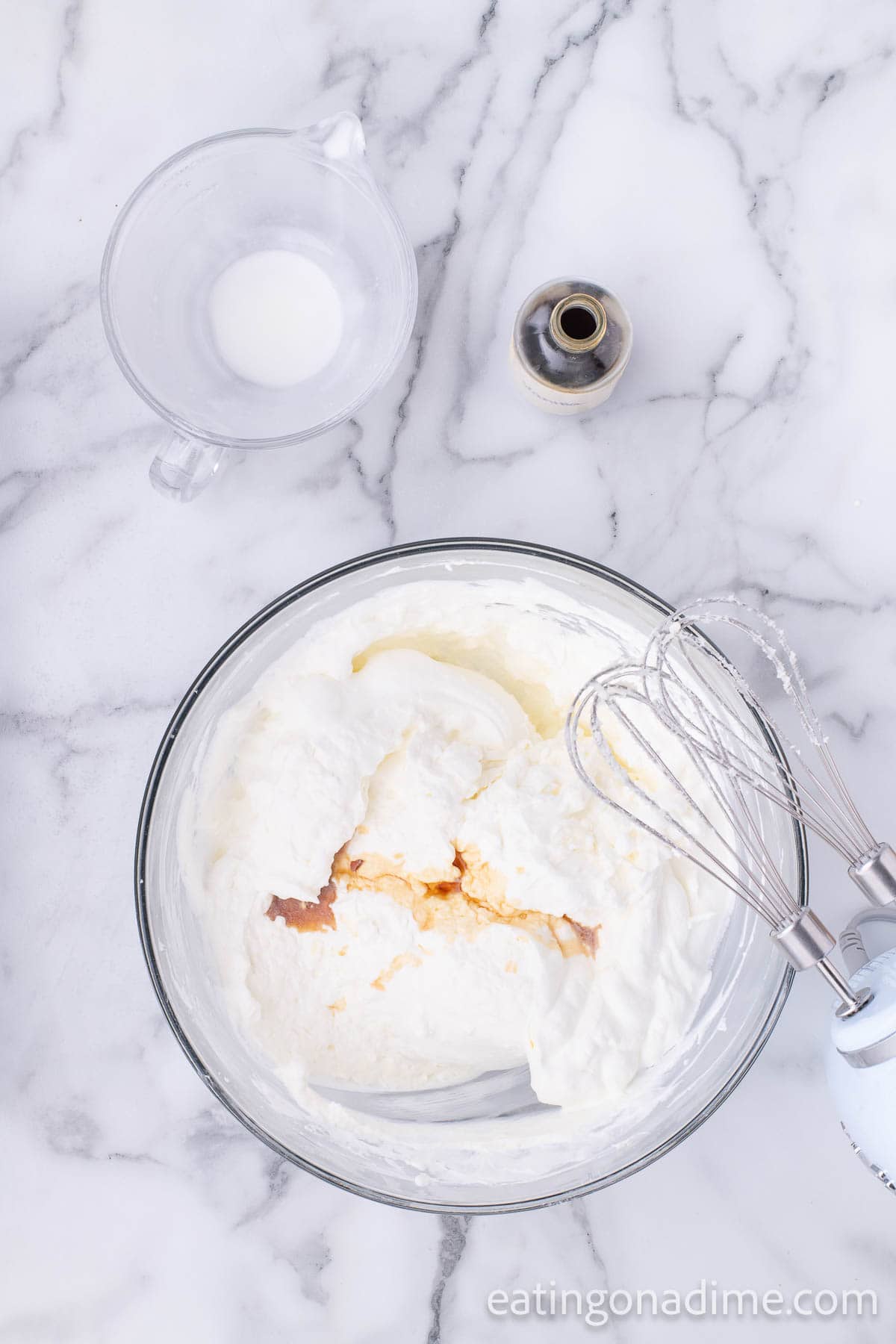 Heavy cream and vanilla extract added to the cream cheese mixture in a bowl