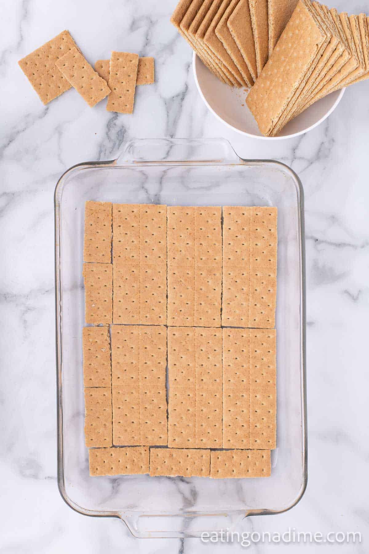 Graham Crackers placed in a glass baking dish with a graham crackers on the side