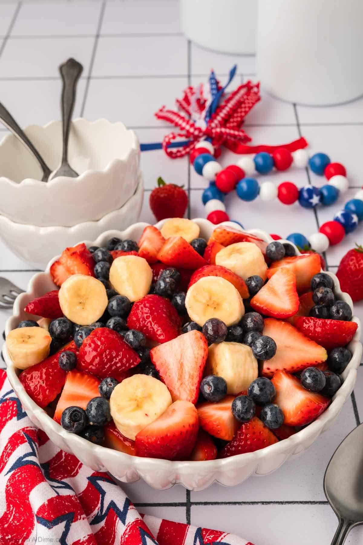 Slice bananas, strawberries, and blueberries in a bowl mixed with a glaze