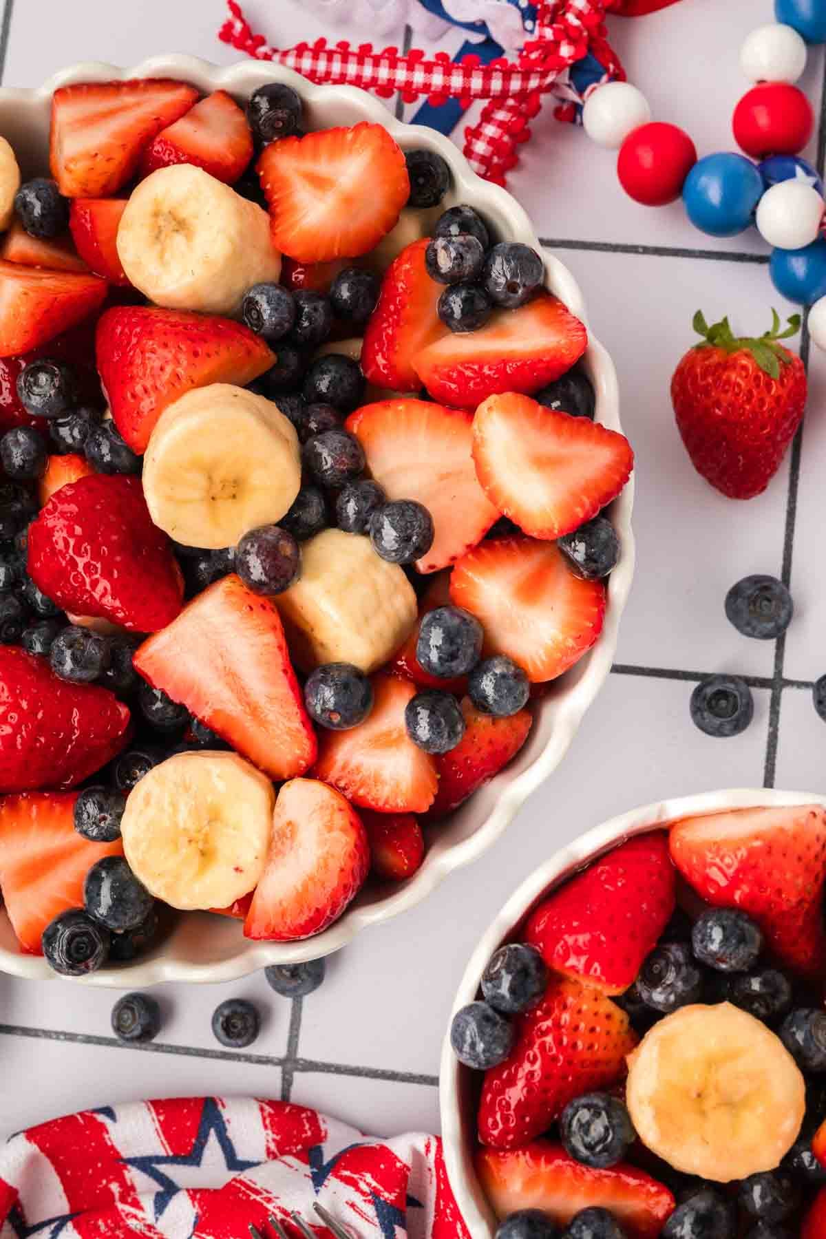 Strawberries, bananas and blueberries mixed together in a bowl with honey lime dressing.