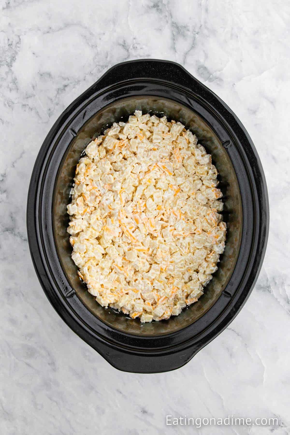 Placing the combined hash browns in the slow cooker