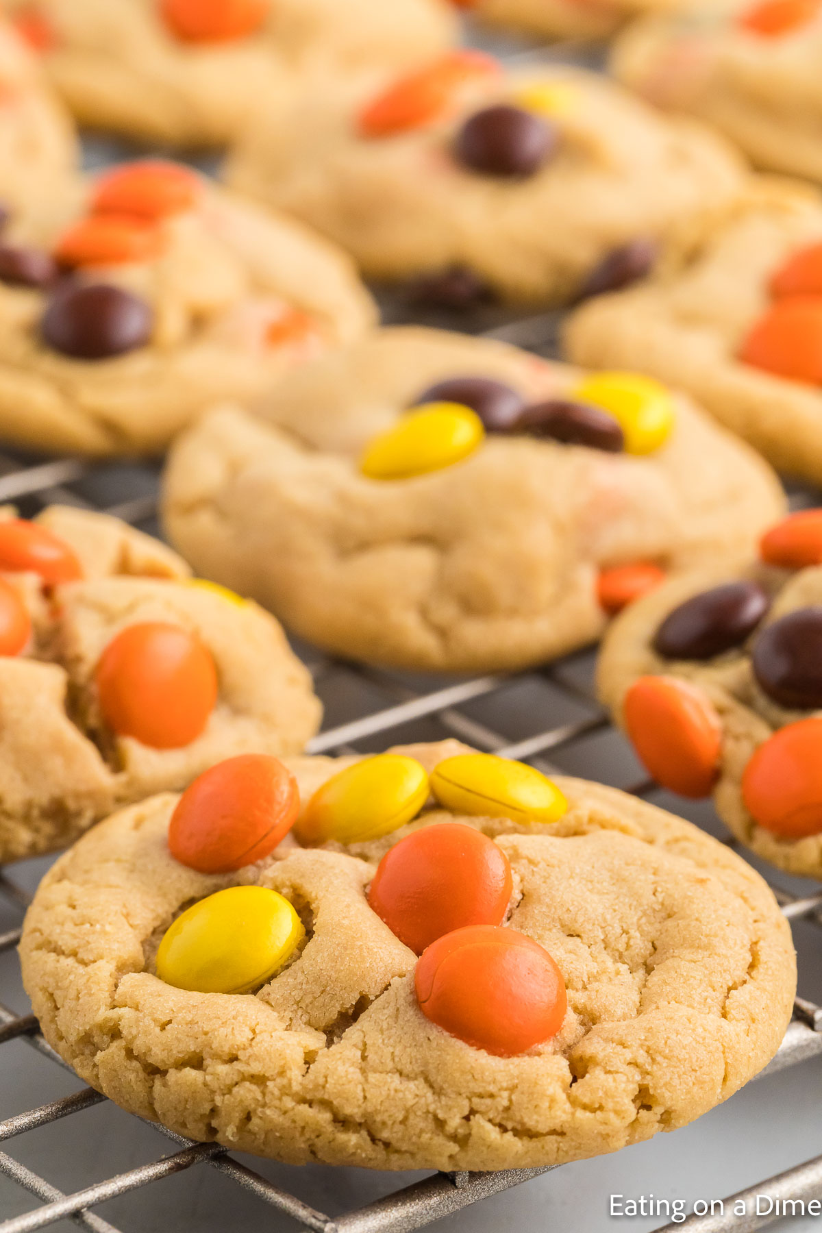Close up image of Reese's Pieces Cookies stacked on a wire rack