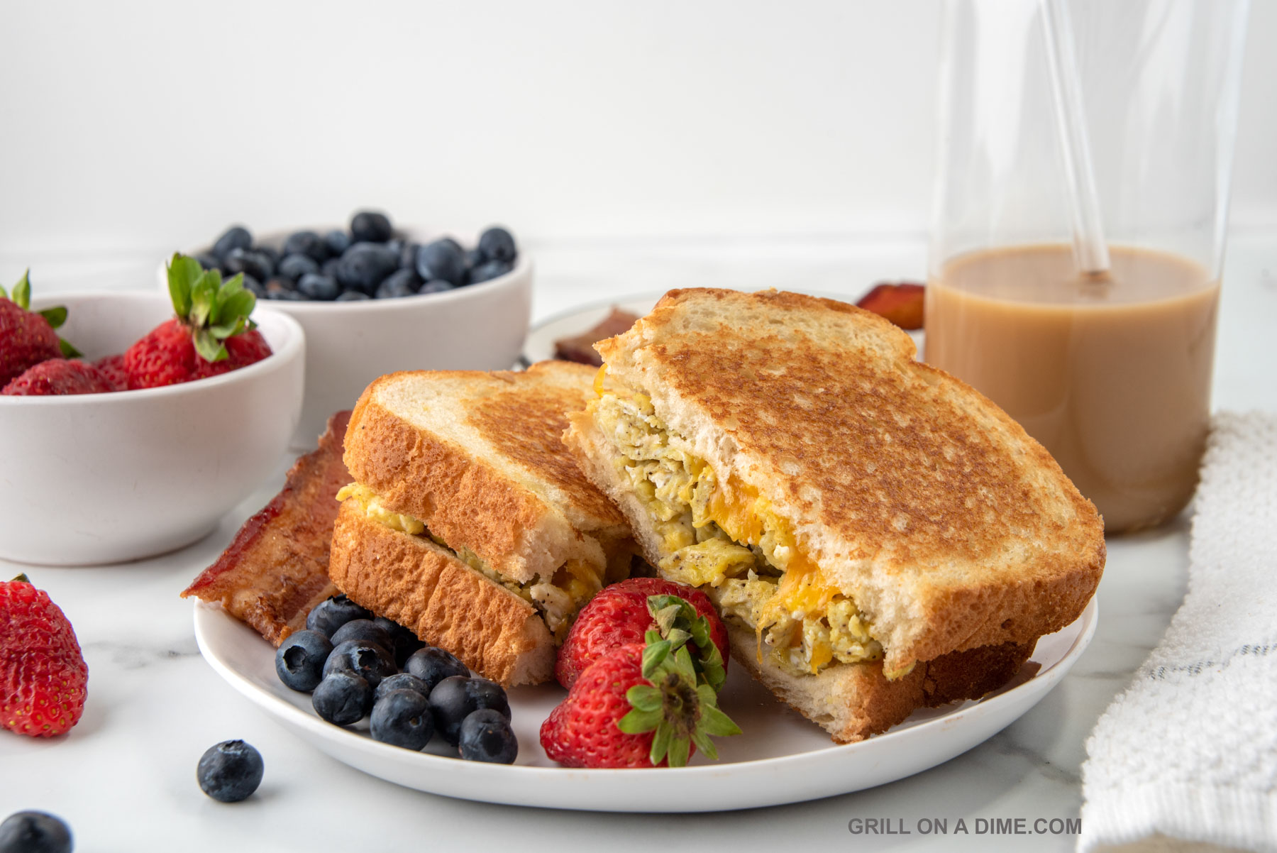 Scrambled Egg Sandwich on a plate with a side of blueberries and strawberries