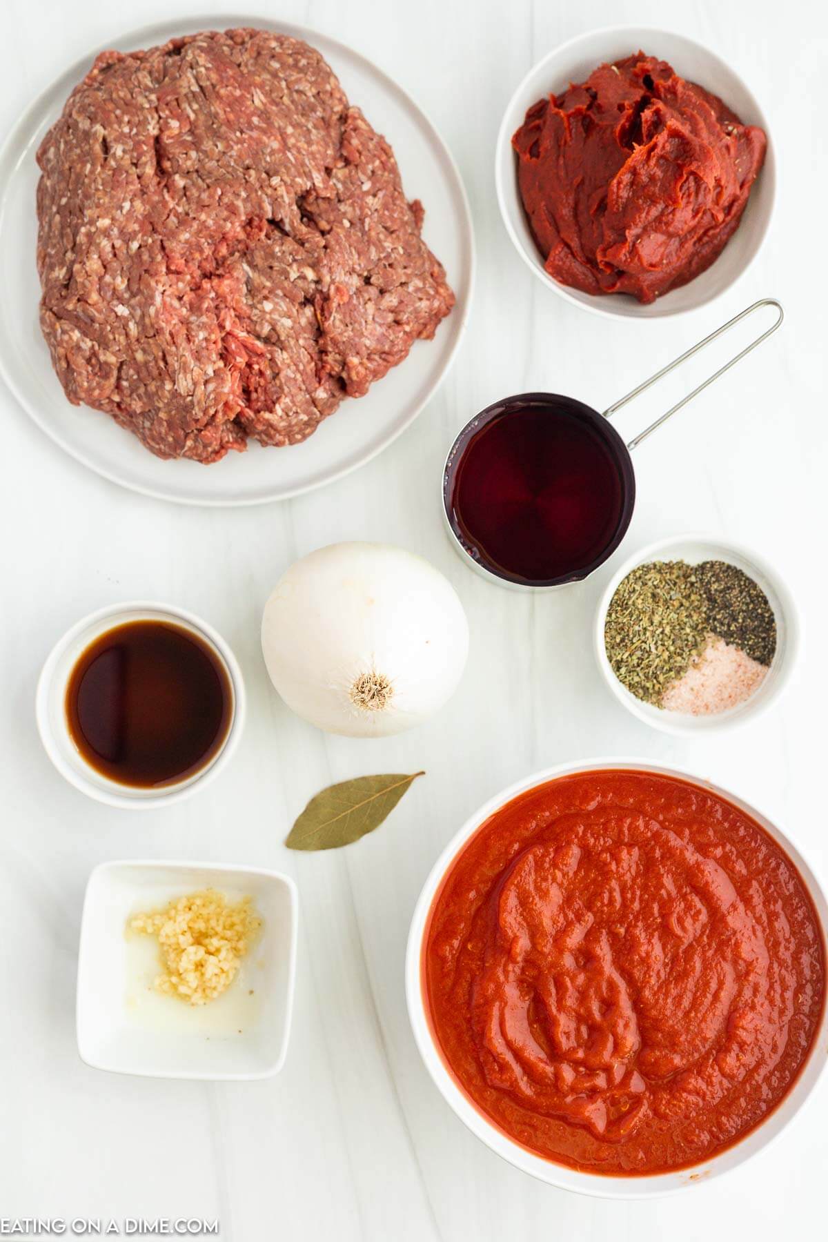 Bolognese Sauce ingredients - ground beef, onion, crushed tomatoes, tomato paste, worcestershire sauce, Italian seasoning, garlic, salt and pepper, bay leaf, red wine, chicken broth