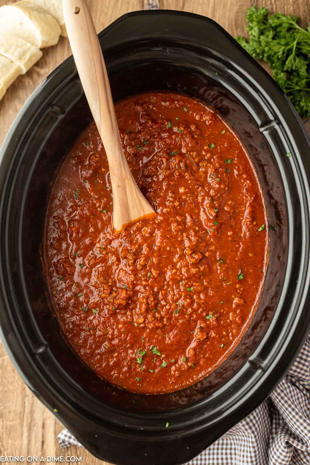 spaghetti sauce in the slow cooker with a wooden spoon