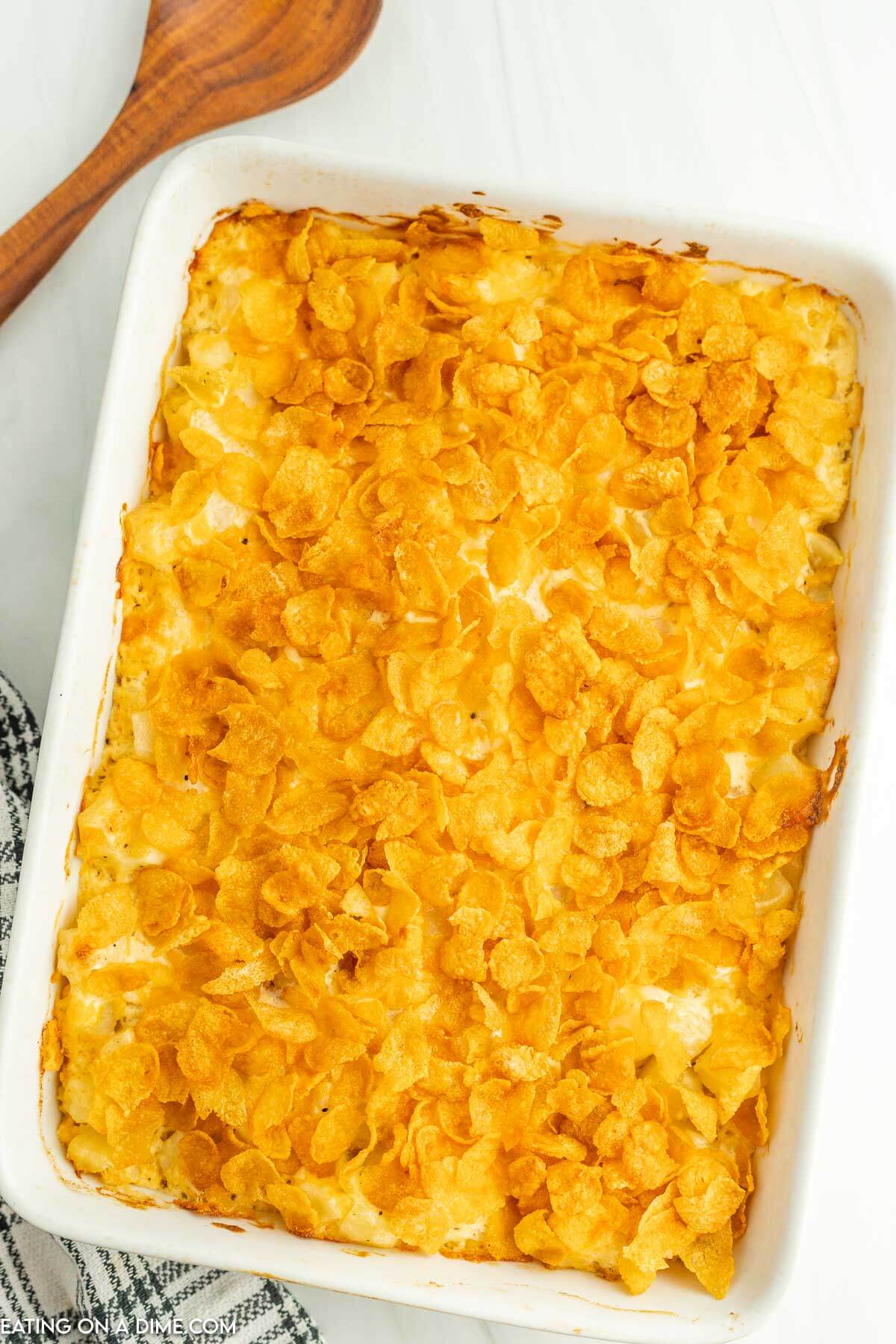 funeral potatoes in a casserole dish with a wooden spoon