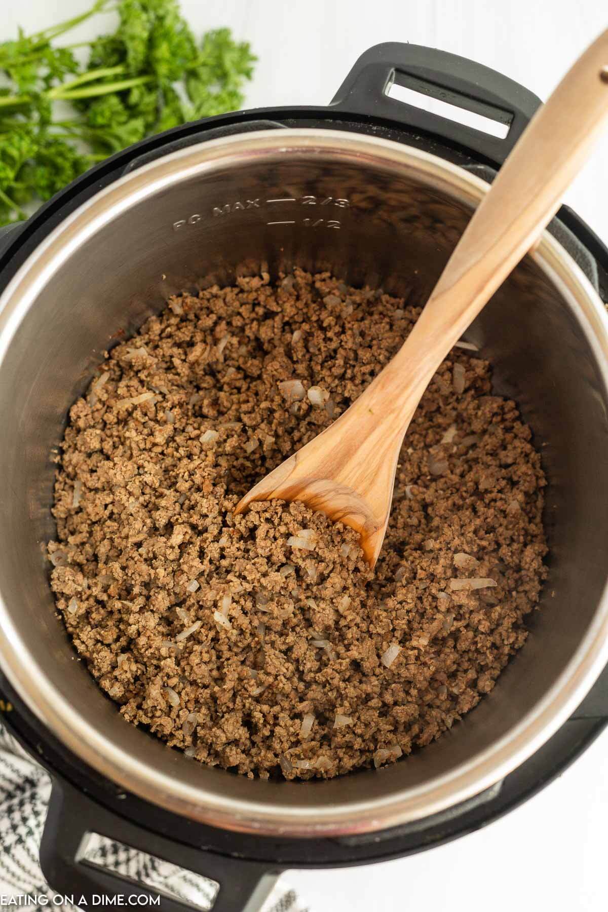 Cooked ground beef in the instant pot with a wooden spoon