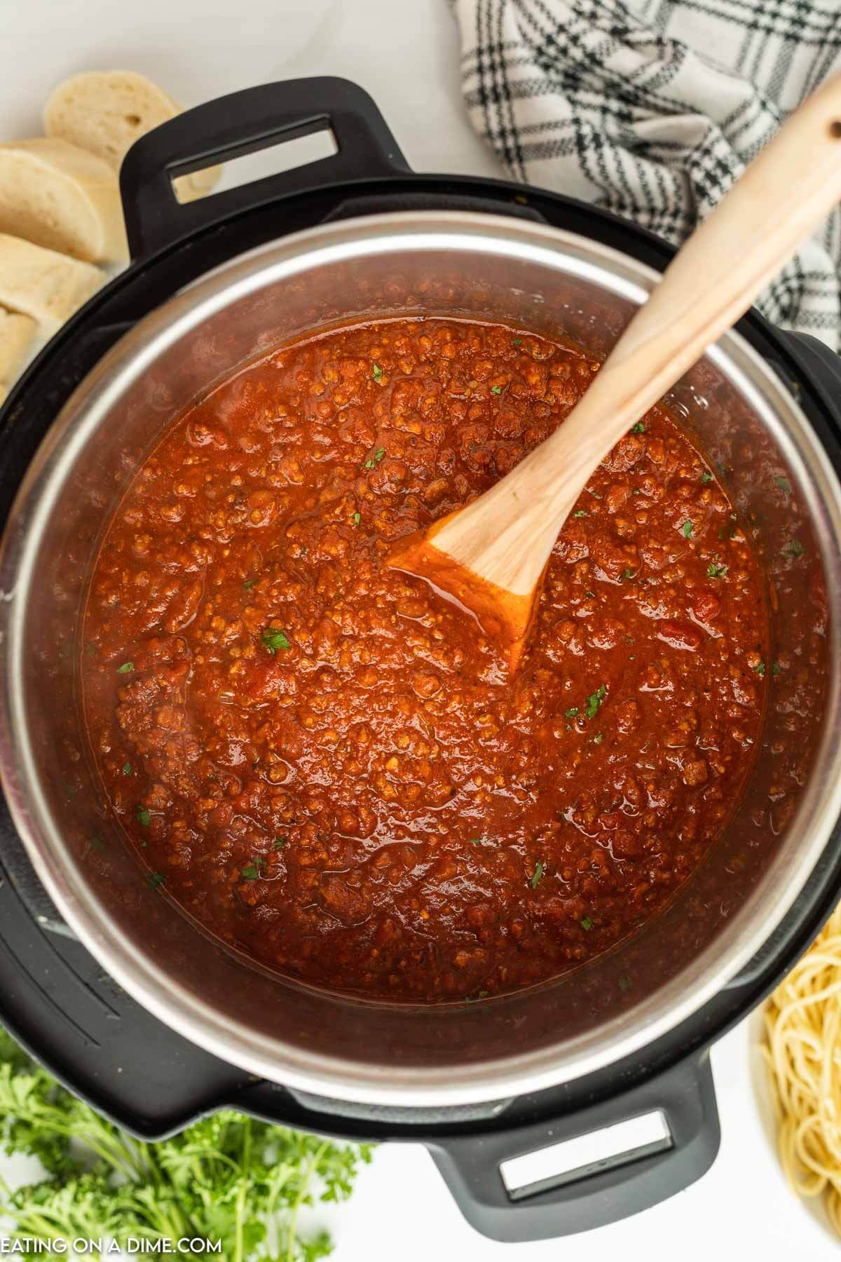 Bolognese sauce in the instant pot with a wooden spoon