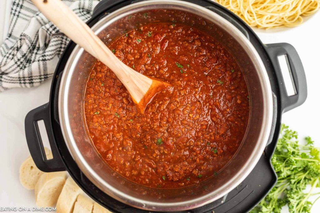 Bolognese Sauce in the instant pot with a wooden spoon