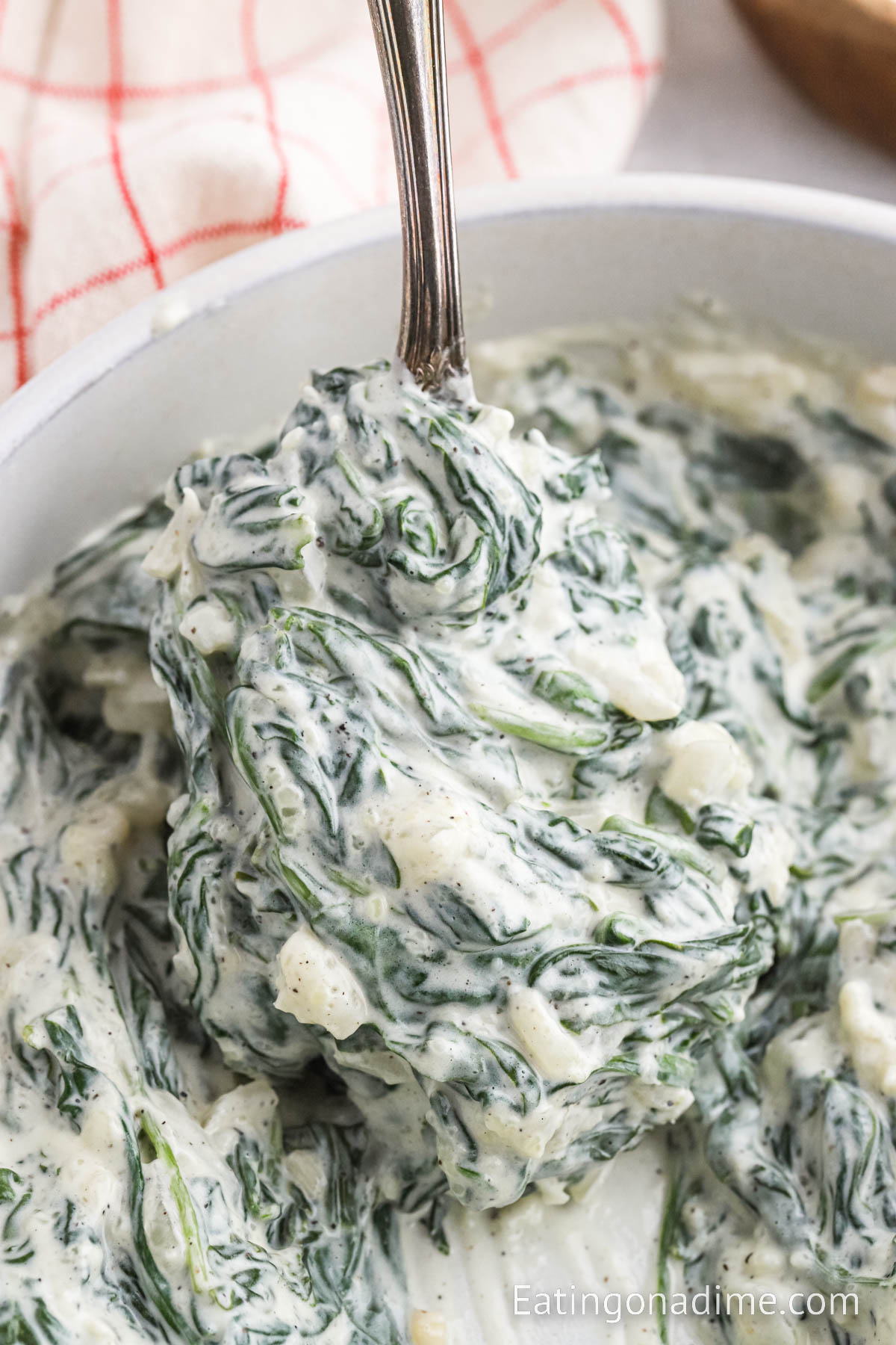 Creamed Spinach in a white bowl in a serving on a spoon