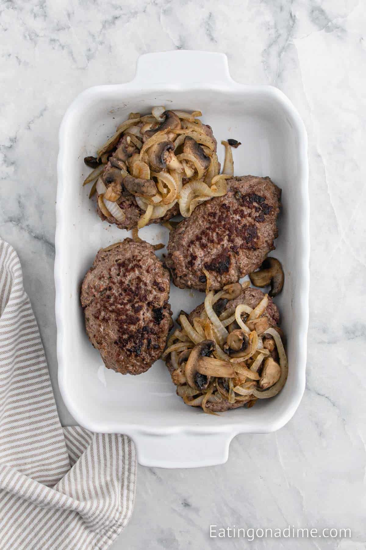 Topping cooked burgers in baking dish with onion mixture