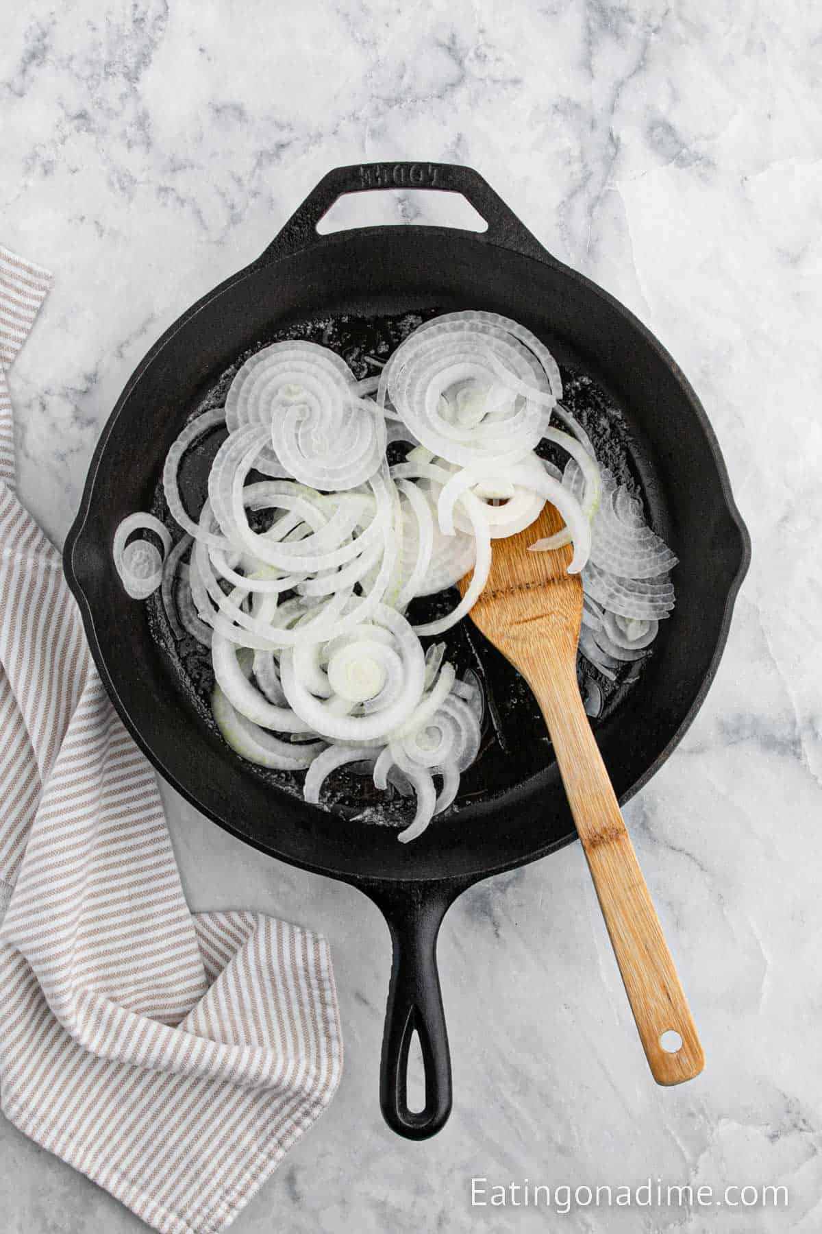 Cooking the slice onions in a cast iron skillet with a wooden spoon