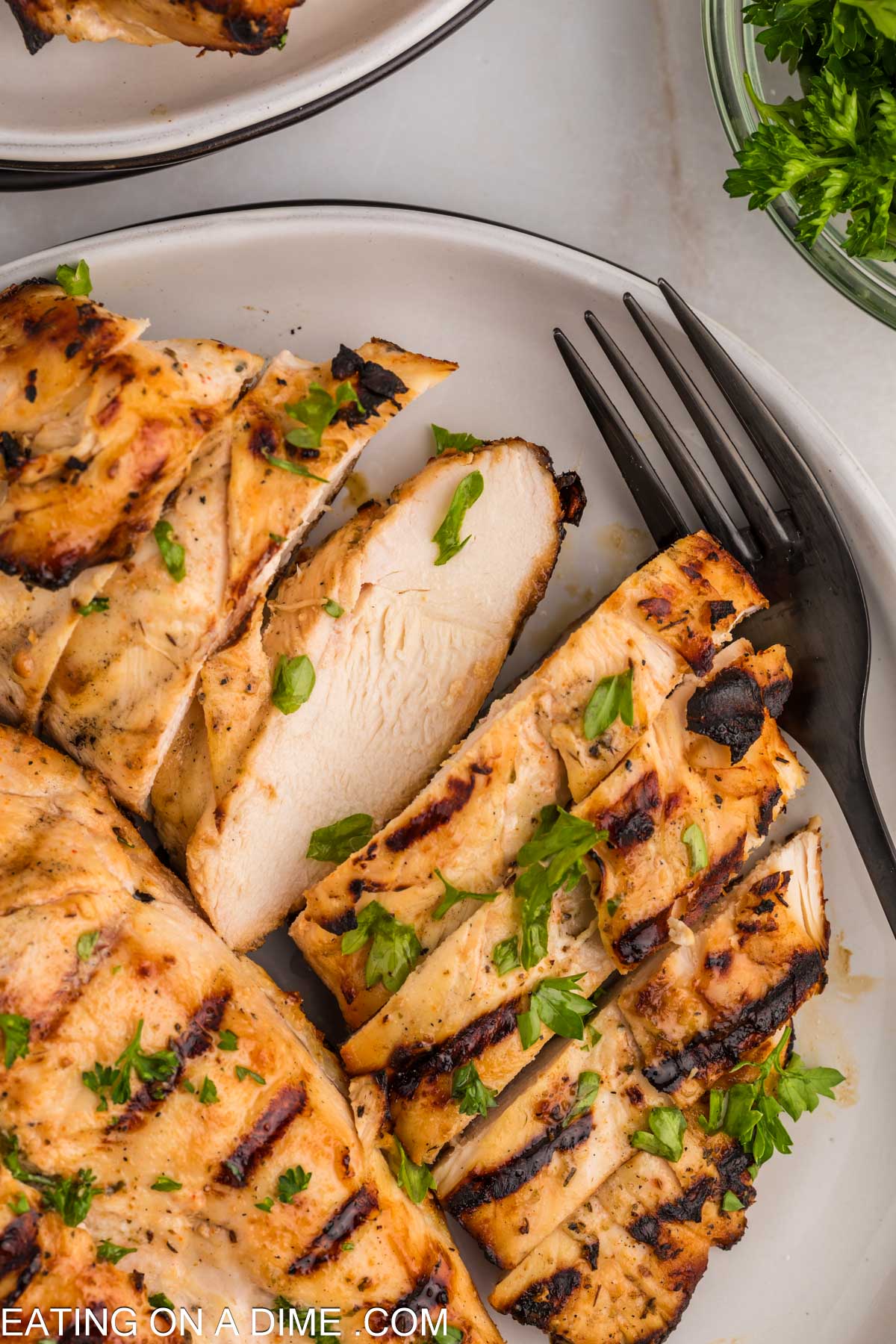 Slice grilled chicken on a plate