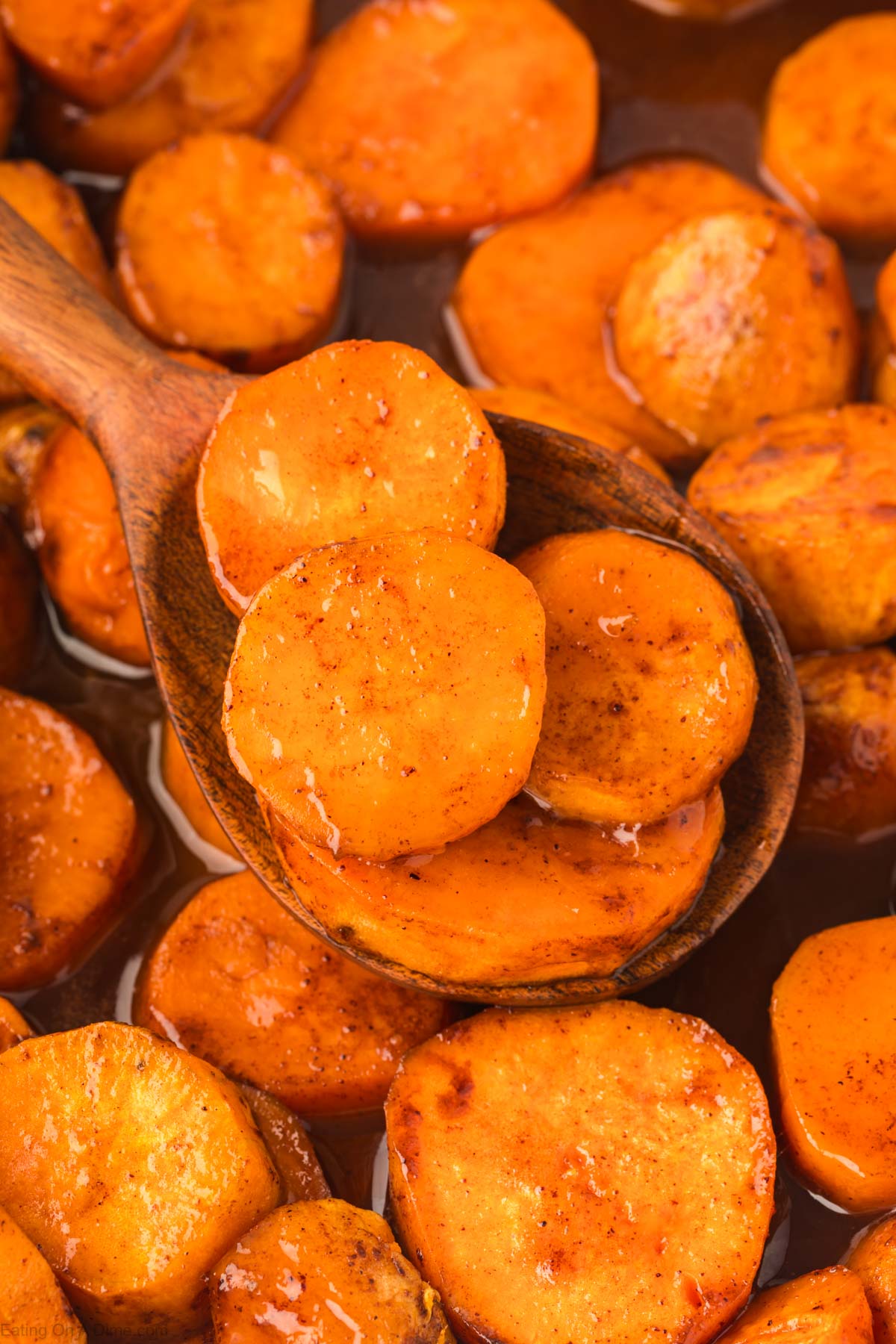 Candied Yams in a casserole dish with a wooden spoon