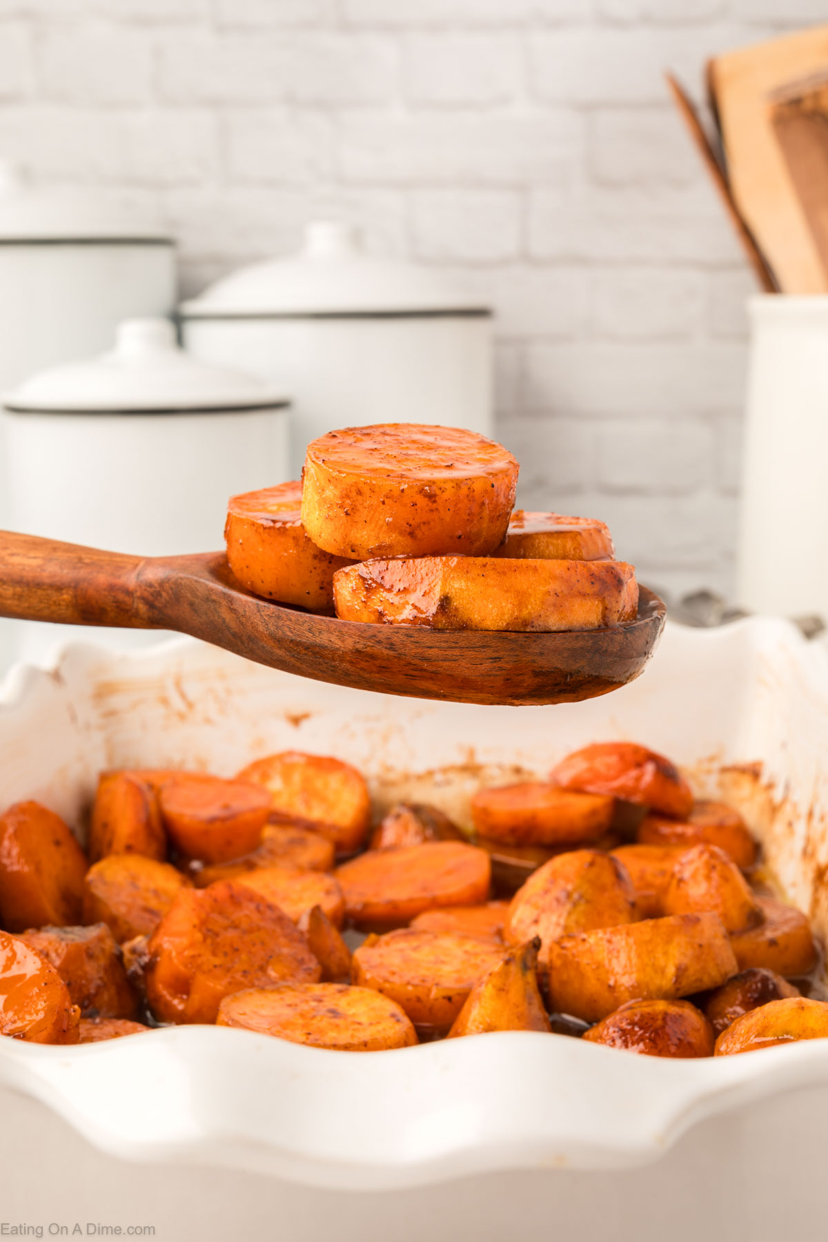 Candied Yams in a casserole dish with a wooden spoon