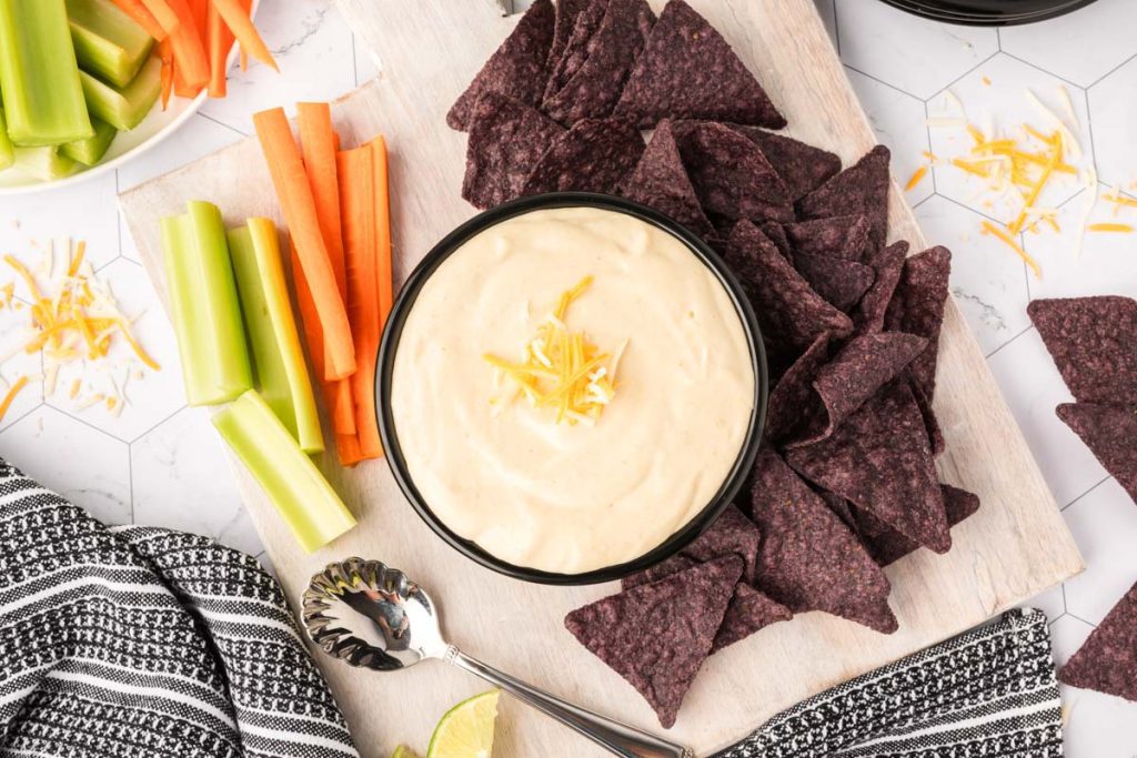 Cottage cheese queso on a plate with chips and raw veggies