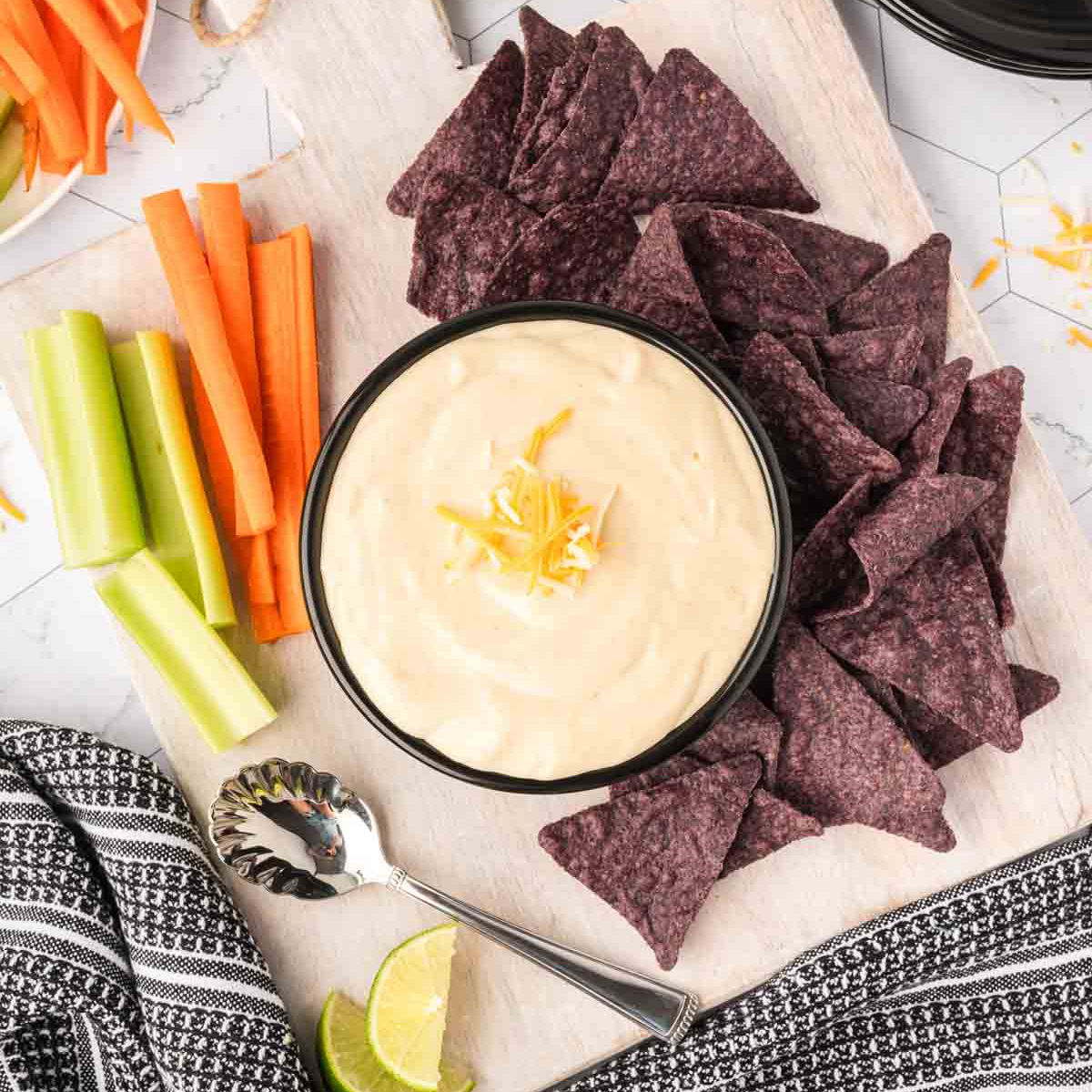 Cottage cheese queso on a plate with chips and raw veggies